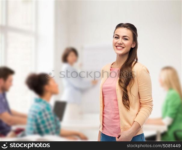 education, high school and people concept - happy smiling young student woman over classroom background. happy smiling young woman in cardigan