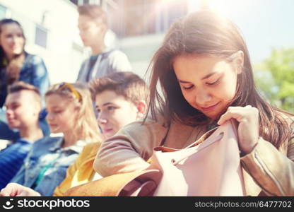 education, high school and people concept - happy teenage student girl looking for something in her backpack outdoors. high school student girl with backpack outdoors. high school student girl with backpack outdoors