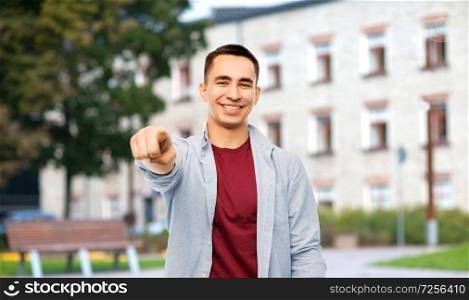 education, high school and people concept - man pointing finger to you over campus building background. man pointing finger to you over campus background