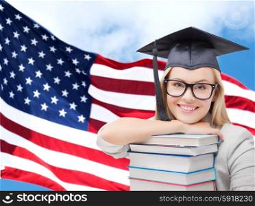 education, high school, knowledge and people concept - picture of happy student girl or woman in trencher cap with stack of books over american flag background