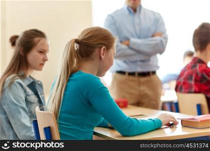 education, high school, learning and people concept - sad student girl with bad test result and teacher in classroom