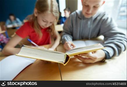 education, high school, learning and people concept - students with book writing to notebooks on lesson