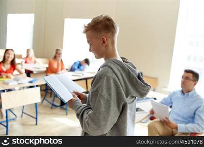 education, high school, learning, examination and people concept - student boy with notebook and teacher in classroom