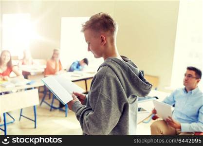 education, high school, learning, examination and people concept - student boy with notebook and teacher in classroom. student boy with notebook and teacher at school