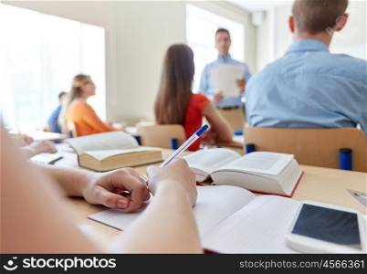 education, high school, learning, technology and people concept - close up of student hands writing to notebook and smartphone on desk