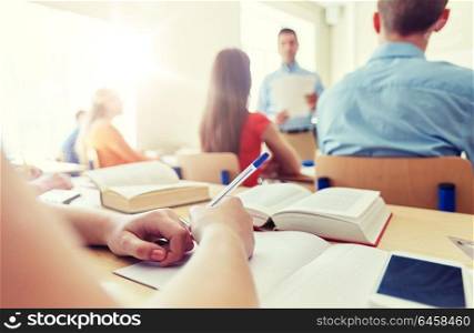 education, high school, learning, technology and people concept - close up of student hands writing to notebook and smartphone on desk. student with smartphone and notebook at school