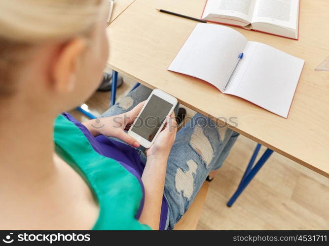 education, high school, learning, technology and people concept - student girl with smartphone texting on lesson