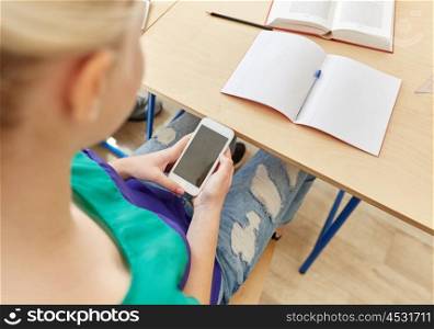 education, high school, learning, technology and people concept - student girl with smartphone texting on lesson