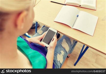 education, high school, learning, technology and people concept - student girl with smartphone texting on lesson. student girl with smartphone texting at school