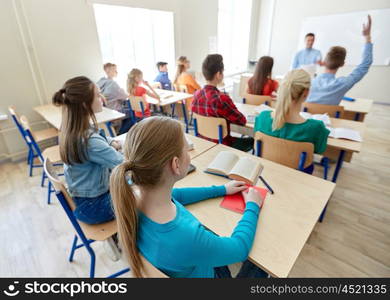 education, high school, teaching, learning and people concept - group of happy students raising hands and teacher in classroom