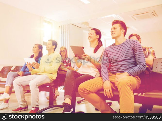 education, high school, teamwork and people concept - group of smiling students with tablet pc computers sitting in lecture hall