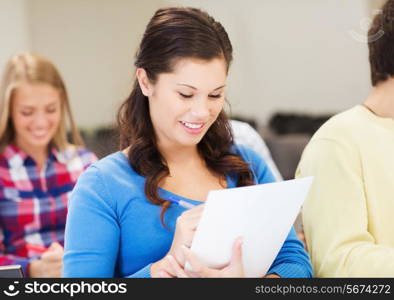 education, high school, teamwork and people concept - group of smiling students with notebook sitting in lecture hall and writing