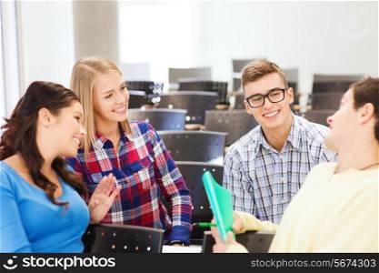 education, high school, teamwork and people concept - group of smiling students with notebook sitting in lecture hall and talking