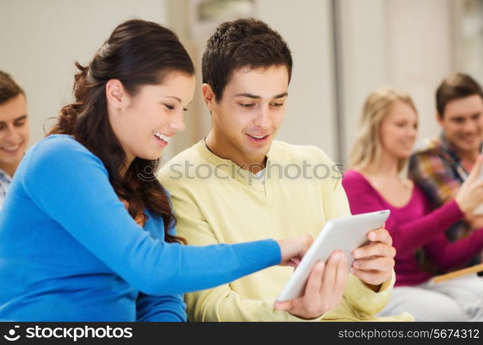 education, high school, teamwork and people concept - group of smiling students with tablet pc computers sitting in lecture hall