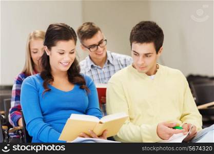 education, high school, teamwork and people concept - group of smiling students with notebooks and books writing in lecture hall
