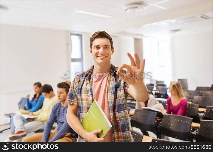 education, high school, teamwork and people concept - group of smiling students with notepads showing ok gesture in lecture hall