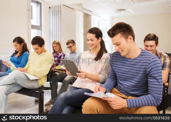 education, high school, teamwork and people concept - group of smiling students with tablet pc computers sitting in lecture hall
