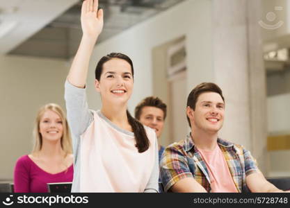 education, high school, teamwork and people concept - group of smiling students raising hand in lecture hall