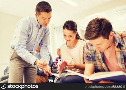 education, high school, teamwork and people concept - group of smiling students and teacher with notebook in classroom