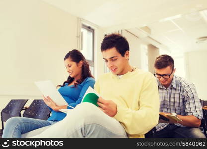 education, high school, teamwork and people concept - group of smiling students with notepads sitting in lecture hall