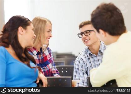 education, high school, teamwork and people concept - group of smiling students sitting and talking in lecture hall