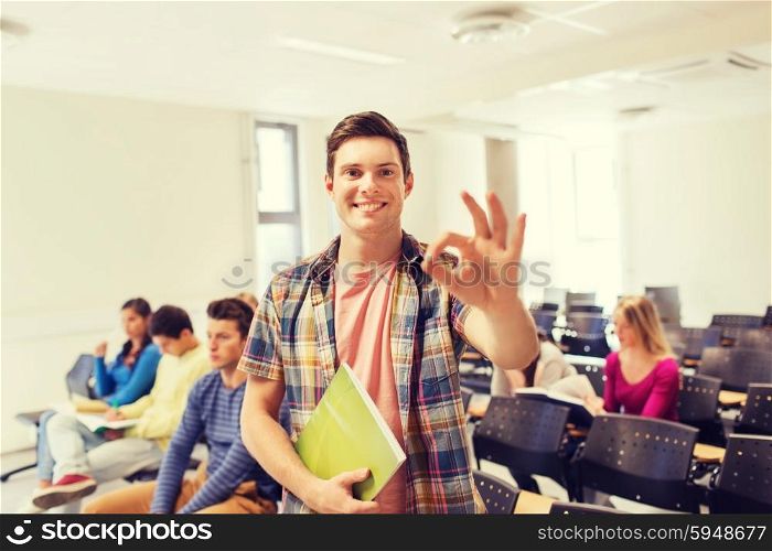 education, high school, teamwork and people concept - group of smiling students with notepads showing ok gesture in lecture hall