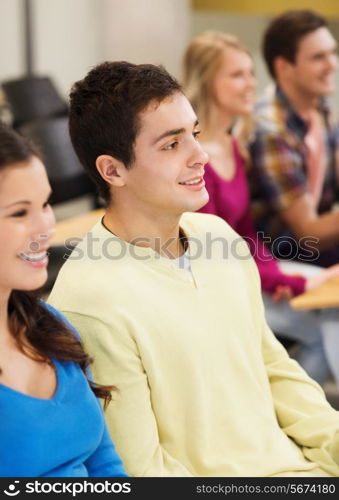 education, high school, teamwork and people concept - group of smiling students sitting in lecture hall