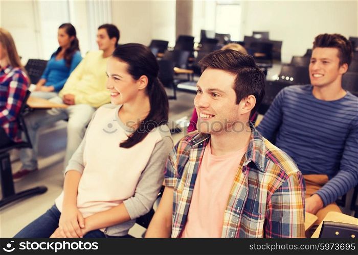 education, high school, teamwork and people concept - group of smiling students sitting in lecture hall