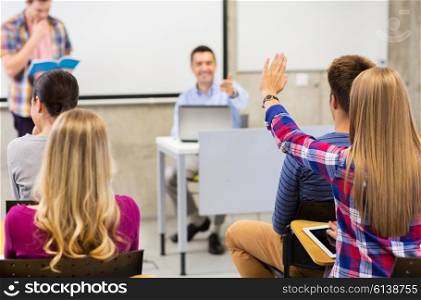 education, high school, teamwork and people concept - group of students raising hand and teacher in lecture hall or classroom