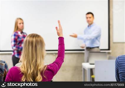 education, high school, teamwork and people concept - group of students raising hand in lecture hall