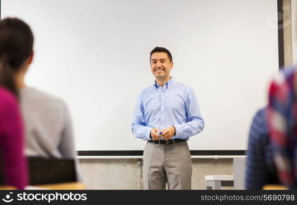 education, high school, teamwork and people concept - smiling teacher standing in front of white board and students in classroom