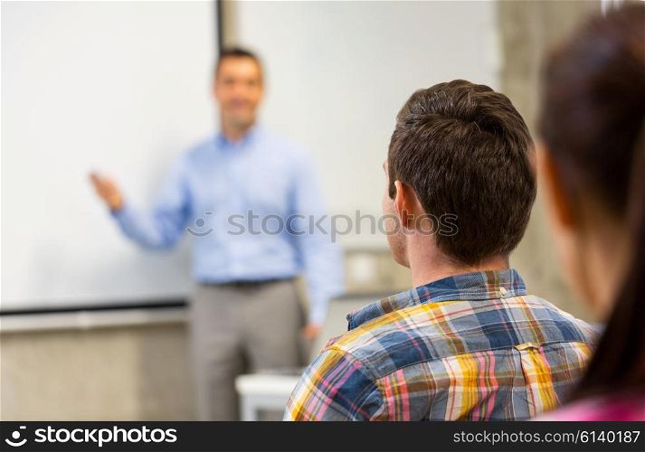 education, high school, teamwork and people concept - teacher standing in front of students and showing something on white board in classroom