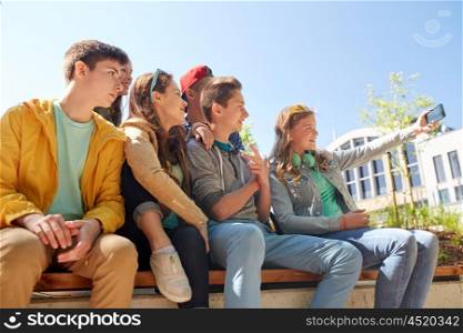 education, high school, technology and people concept - group of happy teenage students or friends taking selfie by smartphone