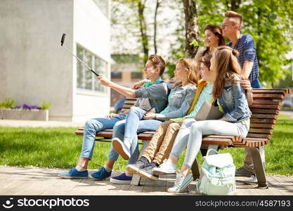 education, high school, technology and people concept - group of happy teenage students or friends taking selfie by smartphone and monopod