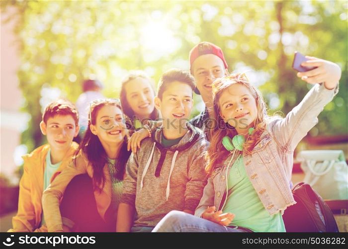 education, high school, technology and people concept - group of happy teenage students or friends taking selfie by smartphone. happy teenage students taking selfie by smartphone