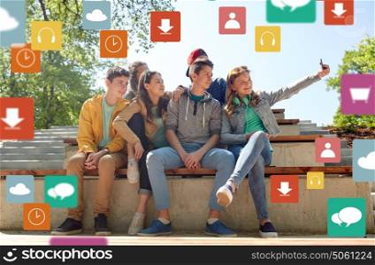 education, high school, technology and people concept - group of happy teenage students or friends taking selfie by smartphone over media icons. happy teenage students taking selfie by smartphone