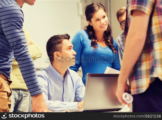 education, high school, technology and people concept - group of smiling students and teacher with papers, laptop computer in classroom