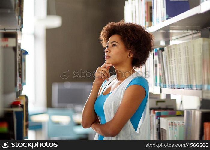 education, high school, university, learning and people concept - african american student girl choosing book at library