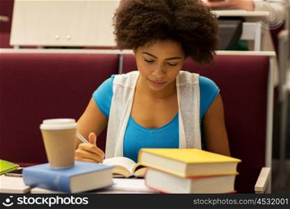 education, high school, university, learning and people concept - african student girl with books and coffee on lecture