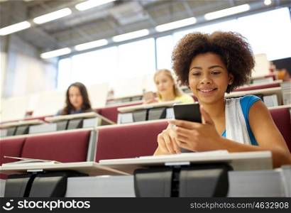 education, high school, university, learning and people concept - african student girl with smartphone at lecture