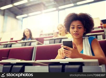 education, high school, university, learning and people concept - african student girl with smartphone at lecture. african student girl with smartphone at lecture
