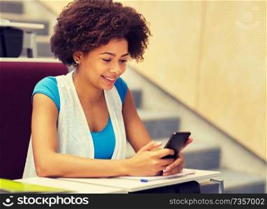 education, high school, university, learning and people concept - african student girl with smartphone on lecture. african student girl with smartphone on lecture
