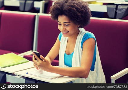 education, high school, university, learning and people concept - african student girl with smartphone on lecture. african student girl with smartphone on lecture