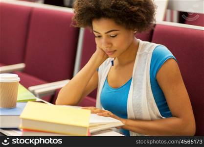 education, high school, university, learning and people concept - bored african student girl with books and coffee on lecture