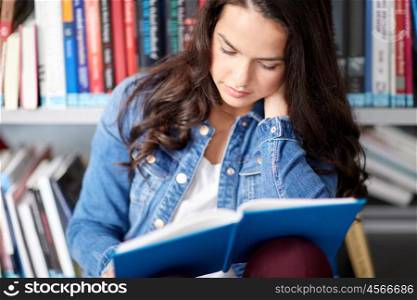 education, high school, university, learning and people concept - close up of student girl reading book sitting on floor at library
