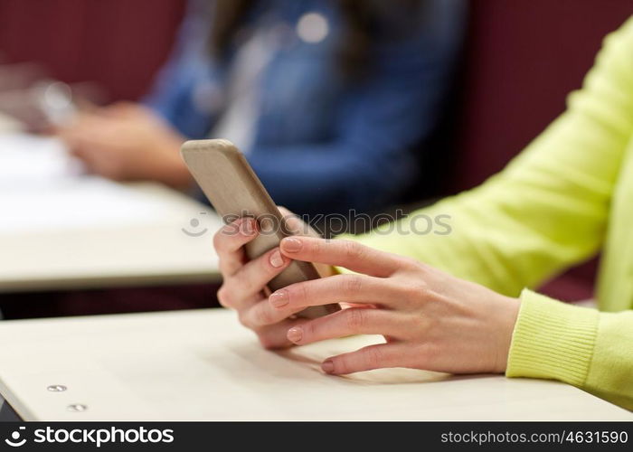 education, high school, university, learning and people concept - close up of student girls with smartphones on lecture