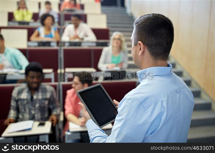 education, high school, university, learning and people concept - close up of teacher with tablet pc computer and students at lecture hall