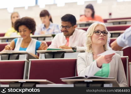 education, high school, university, learning and people concept - group of international students with test in lecture hall