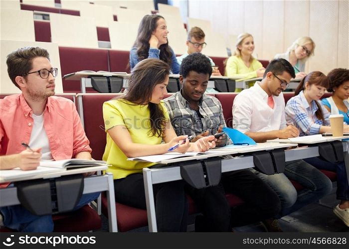 education, high school, university, learning and people concept - group of international students with smartphone at lecture