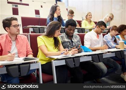 education, high school, university, learning and people concept - group of international students with smartphone at lecture